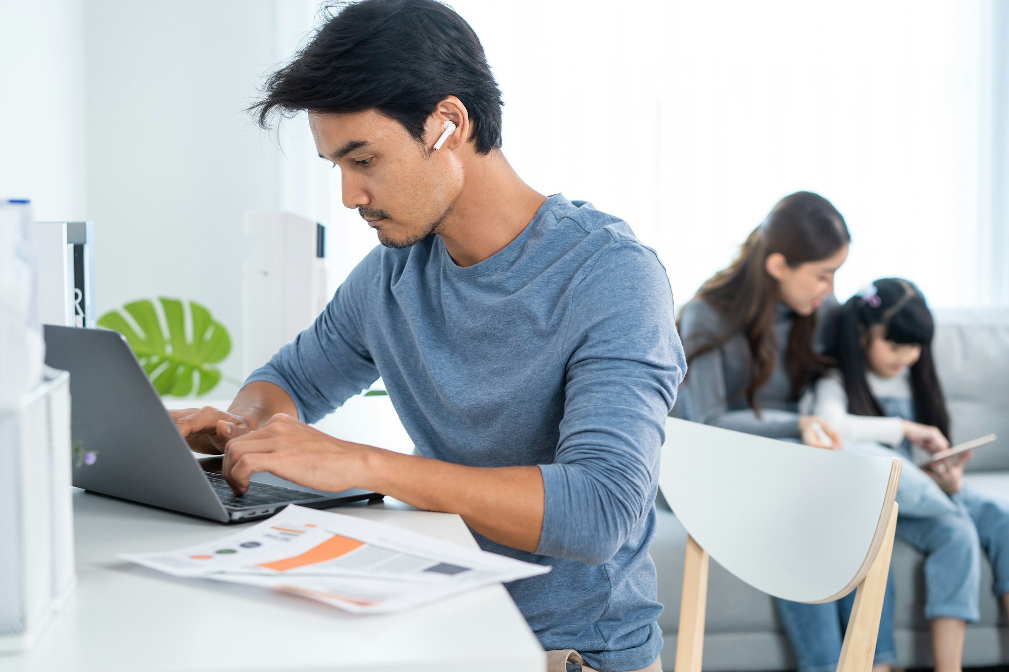 Asian business man father sit on table work at home with family behind.